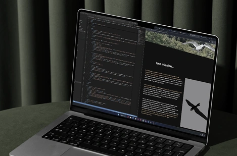 Mock up d'un ordinateur, posé sur une dalle en béton devant des rideaux, affichant le code de mon projet design fiction et le rendu du site (split screen).