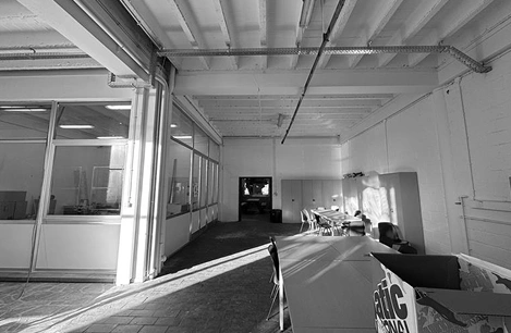 Image originale en nuances de gris de la salle à réaménager. On voit que quelques tables et tables et chaises sont déjà présentes dans la salle.